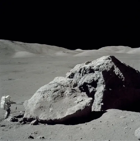 Scientist on the Moon. Photograph of geologist Harrison Schmitt collecting samples near a large boulder on the Lunar surface. Schmitt is at lower left, dwarfed by the massive boulder.