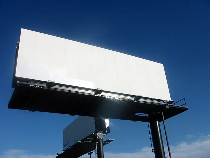 Two billboards are shown against the backdrop of a blue sky. Both billboards are large, wide rectangles. Neither billboard has an ad on it.