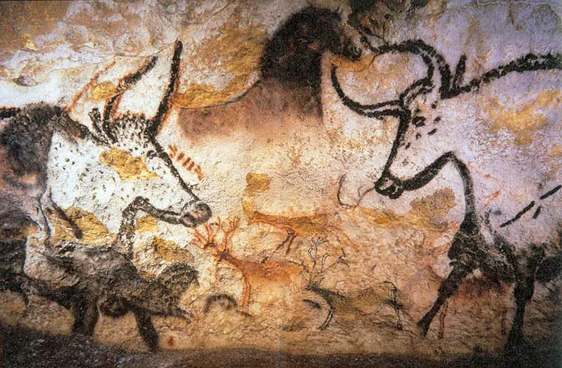 Painting on a cave wall of two horned bulls facing one another. The animal shapes are outlined in lack against the natural color of the background stone.