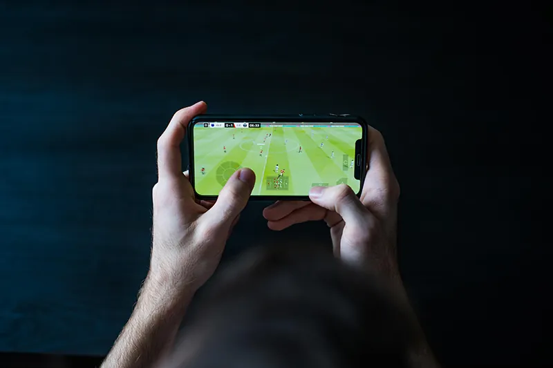 Close-up of a person's two hands playing a video game on a mobile phone.