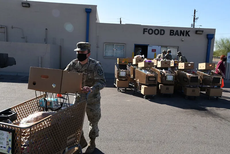 A National Guard soldier at the Glendale, Arizona Food Bank pushes a grocery cart filled with supplies.