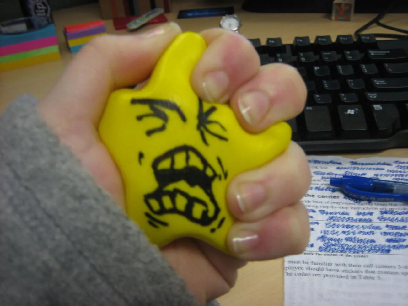 A photo shows a hand squeezing a foam star printed with an angry and yelling face.