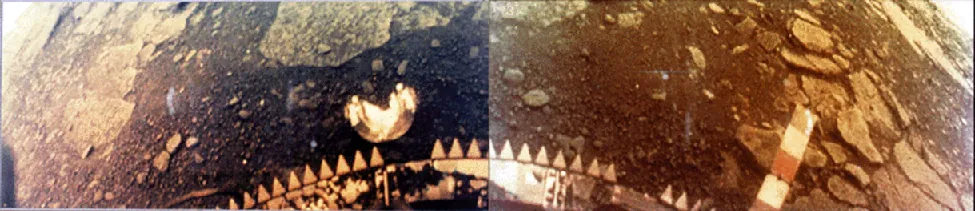 Fisheye view of the surface of Venus. The base of the Venera probe is visible at the bottom center of this photograph while flat rocks and dark soil stretch to the horizon at the upper left and upper right.