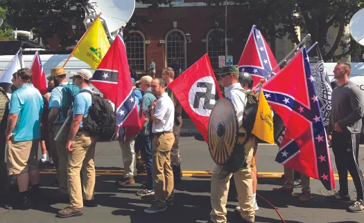 A photograph shows a group of people holding confederate flags and a Nazi flag