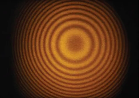 Picture shows a photograph of the fringes produced with a Michelson interferometer. Fringes are visible as alternating dark and light circles.