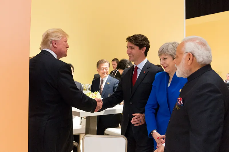 Former President Donald Trump shakes the hand of Canadian Prime Minister Justin Trudeau. Former Prime Minister Theresa May and Prime Minister Narendra Modi stand at Trudeau’s side.