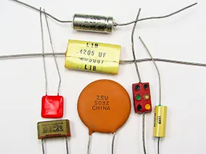 This is a photograph showing seven small capacitors, of varying shapes and colors, usually found in electronic circuits.