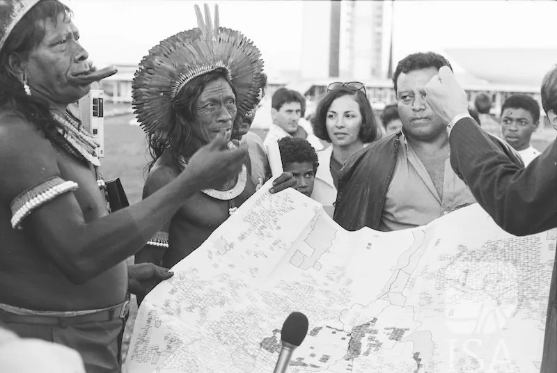 A group of men holding a map and talking animatedly.