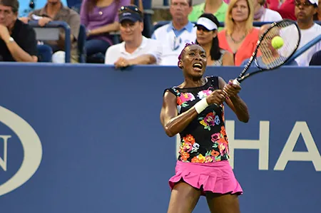 Serena Williams is a famous tennis player. In this image she is hitting a tennis ball with a tennis racket.