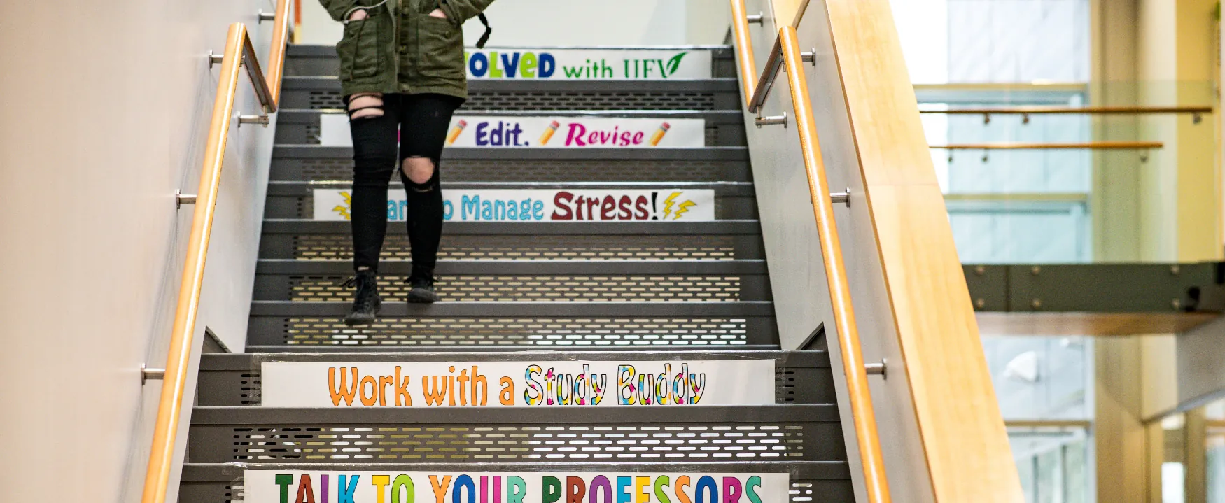 A photo shows the legs of a woman in casual wear walking down the stairs of a building featuring promotional messages including, “Solved with I I F V,” “Work with a Study Buddy,” and “Talk to your professors.”