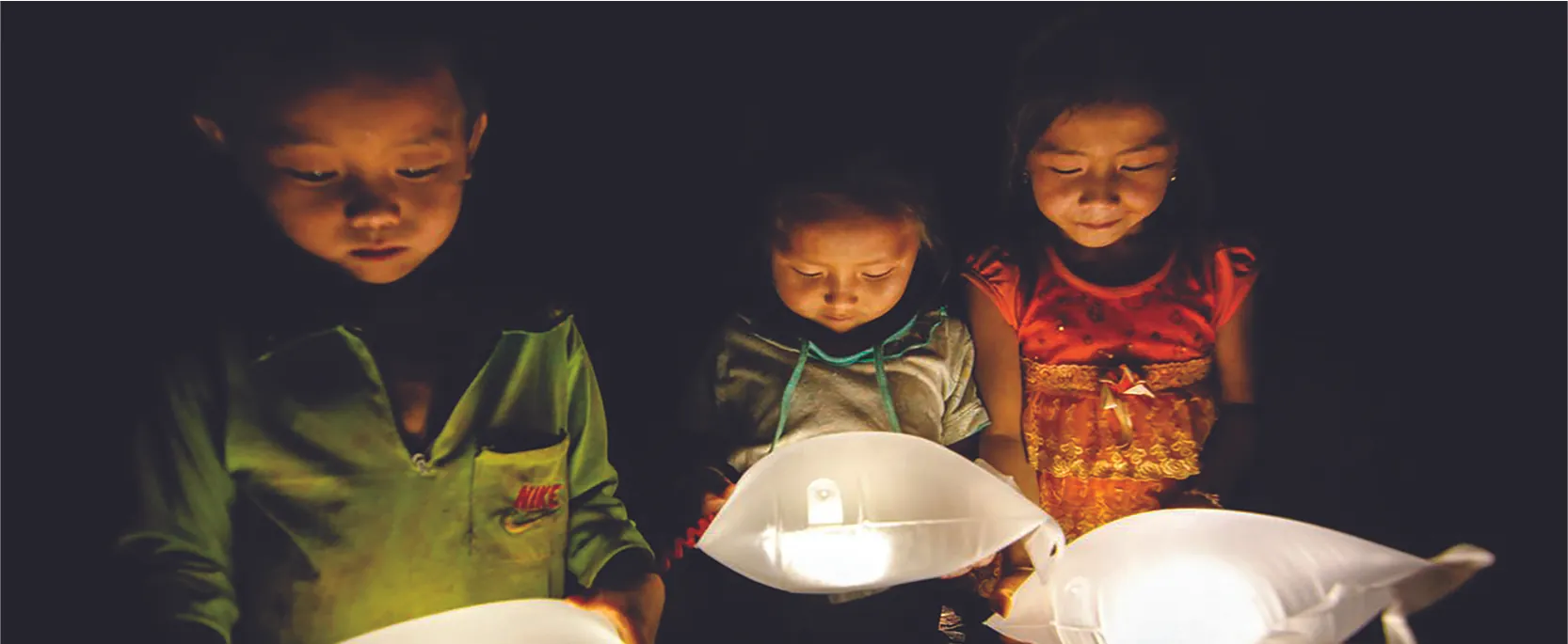 Three children hold white pillow-like objects that emanate light.