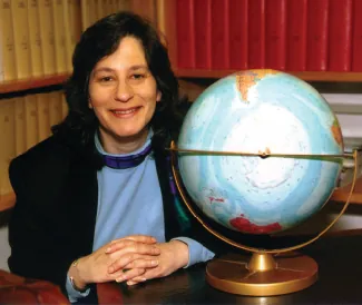 Se muestra una fotografía de Susan Solomon sentada junto a un globo terráqueo.
