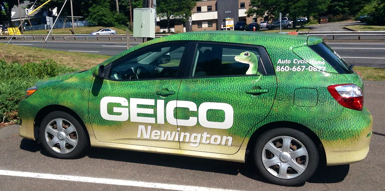 A photograph shows a car whose paint appears like the skin of a gecko. Large lettering reads Geico, and there is a decal of the Geico gecko on the window.