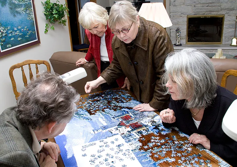 A photo shows four people working together to complete a puzzle.