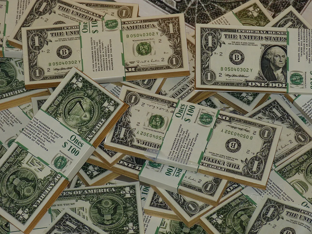 A photo shows dollar bills bundled and wrapped in $100 dollar amounts.