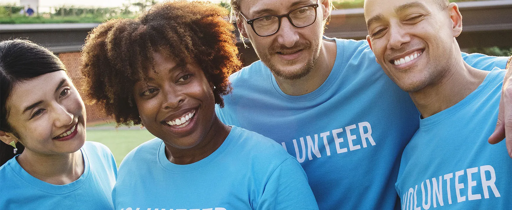 A photograph of a group of men and women smiling. All are wearing shirts bearing the word “volunteer.”