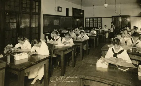 Early 20th century black and white photo showing female students at their desks.