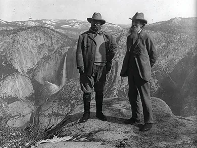 A photograph shows Theodore Roosevelt and John Muir standing atop a precipice in Yosemite National Park.