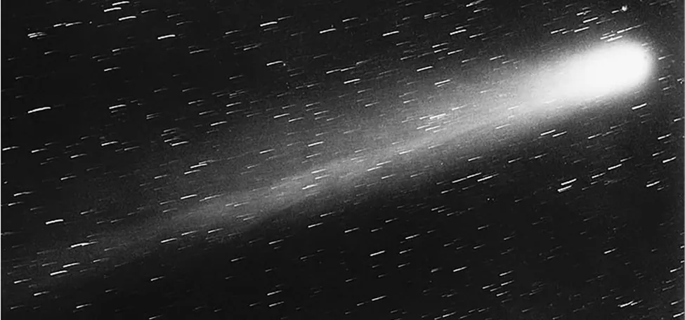 Esta es una imagen del cometa Halley. Es una bola de luz brillante que va hacia la derecha de la imagen con una cola de luz. También hay estrellas en todo el cuadro.