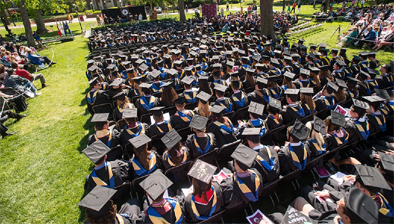 This is a photograph of students at their outdoor college graduation ceremony.