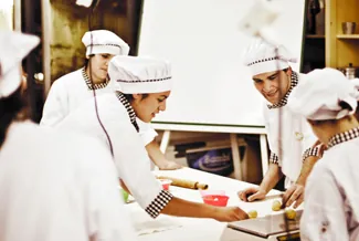 A photograph shows several chefs preparing food together in a kitchen.