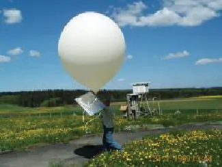 This image shows a white balloon that appears to have an attached white card. The balloon is being held by a person in an outdoor setting.