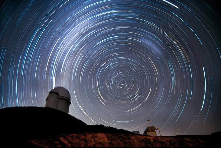 Photograph of Stars Circling the South Celestial Pole. In this time-exposure photograph the stars are not seen as points of light, but as semi-circular arcs due to the rotation of the Earth during the exposure. The domes of several telescopes are silhouetted against the sky.