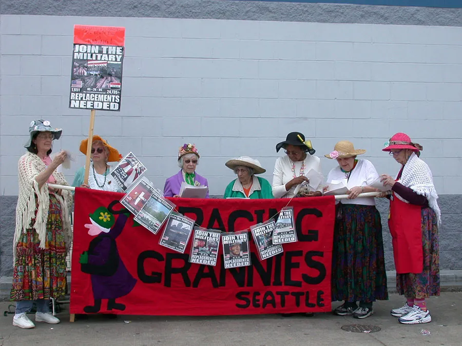 A group of people dress in old-fashioned clothing with signs protesting military recruitment.