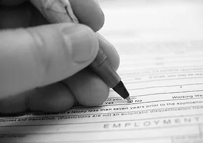 A photo of a person's hand filling in a survey check box labeled 'No' with a pen.