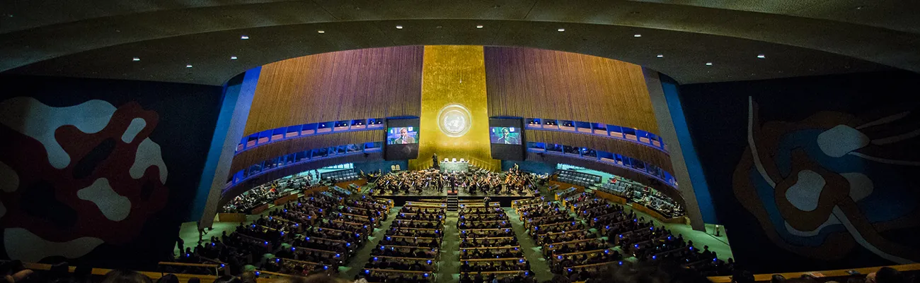 A photo shows a view of the General Assembly Hall, with Alan Gilbert leading the New York Philharmonic on stage to pay a tribute to Ban Ki-moon at the completion of his 10-year term.