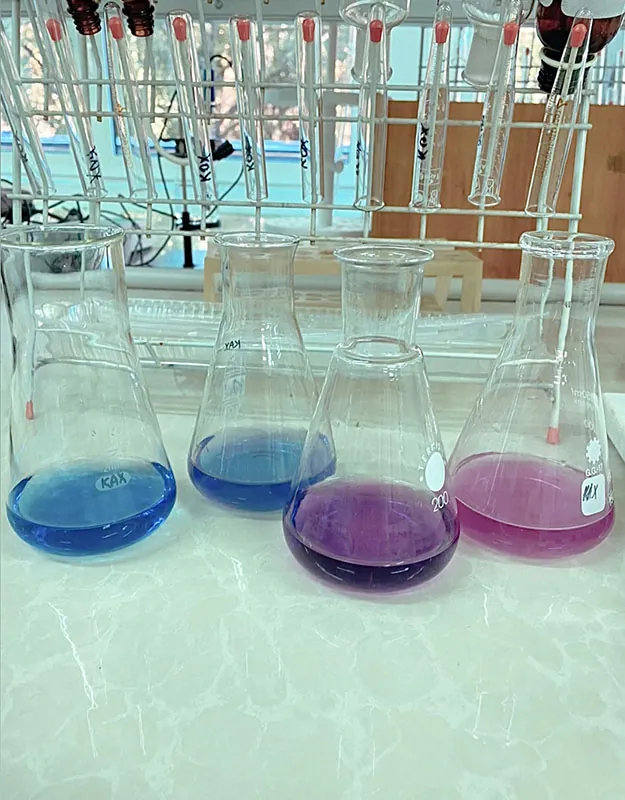 Four lab beakers show blue and purple liquid, the various components of a single substance.