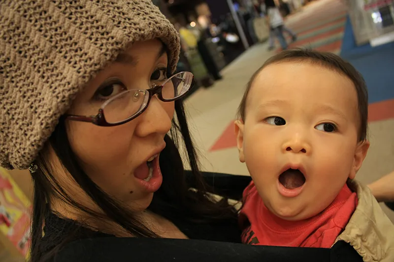 A woman holding a baby, both yawning.