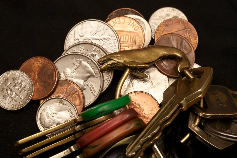 Esta es una foto del cambio de un juego de llaves en una pila. Parece que hay cinco monedas de un centavo, tres de veinticinco centavos, cuatro de diez centavos y dos de cinco centavos. El llavero tiene una ballena de bronce y contiene once llaves.
