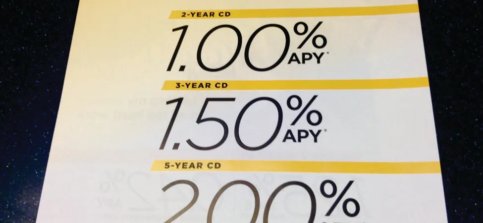 This image shows a sign at a bank indicating annual percentage rates for CDs. The top line says “Earn big with a locked-in rate”. The second line reads 2-year CD with one percent annual percentage rate; the third line reads 3-year CD with a 1.5 percent  annual percentage rate, and the fourth line reads 5-year CD with a 2 percent annual percentage rate.