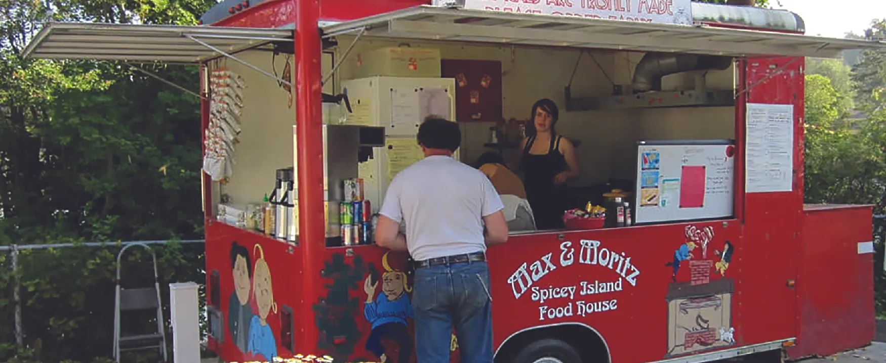 Picture of two people in a food truck serving a customer.
