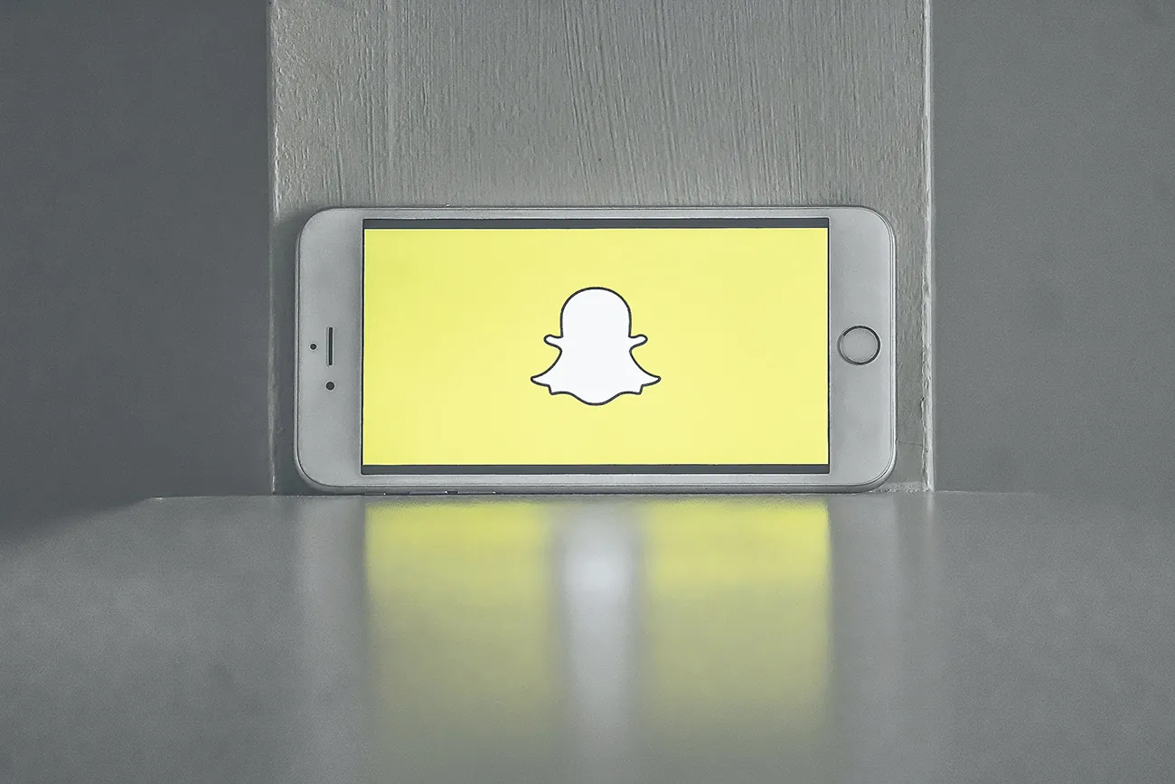A cell phone screen shows the ghost symbol for Snap chat.