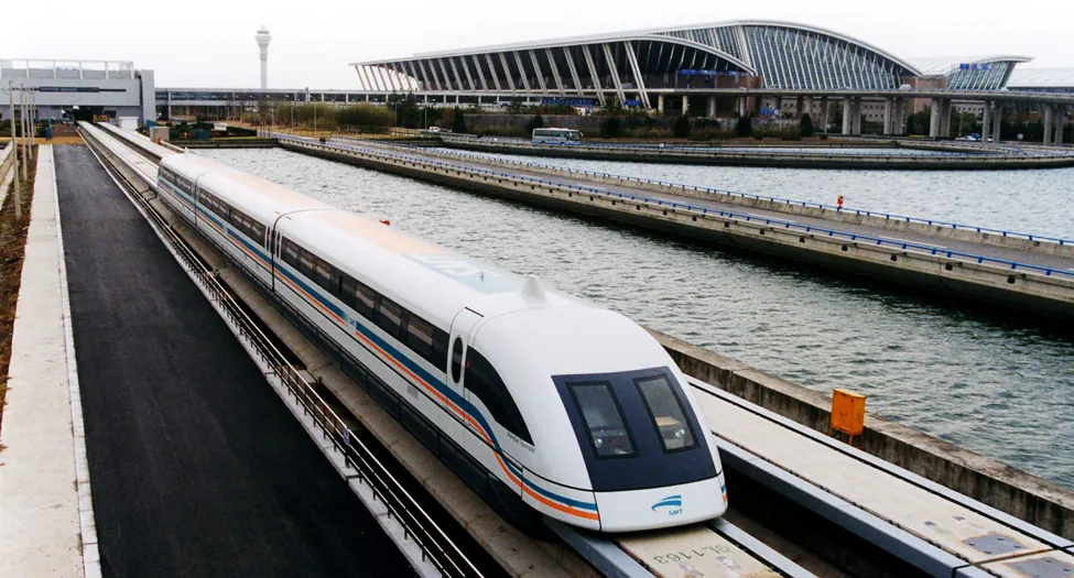 A photograph shows a maglev train traveling past an airport.