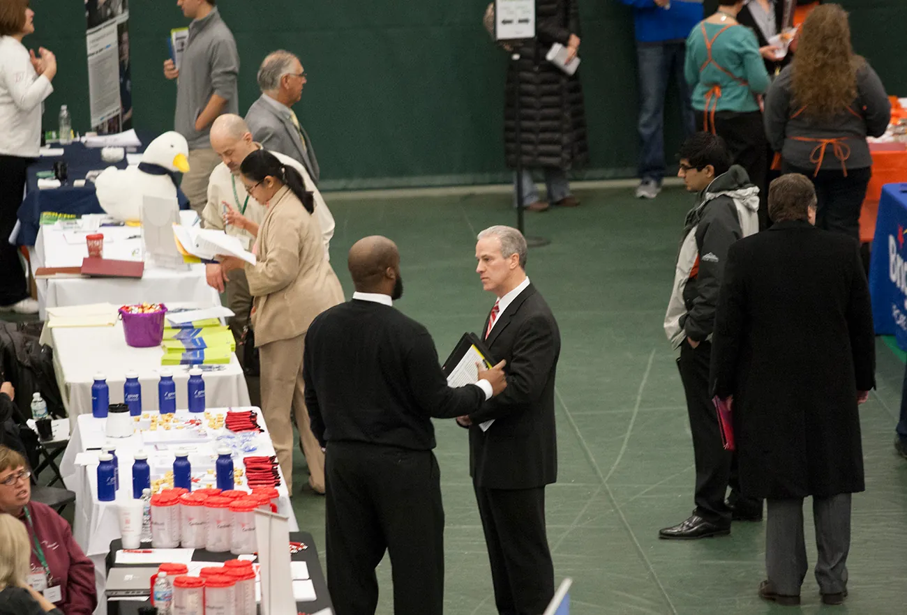 A photo shows recruiters speaking with potential employees and job seekers at a job fair at the College of DuPage.