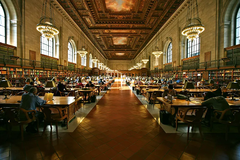 A diverse group of people sit at tables in the New York City Public Library’s Grand Study Hall.