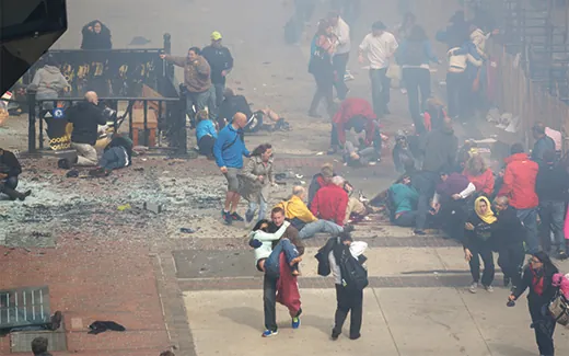 A photograph shows bystanders at the finish line of the Boston Marathon, tending to the injured and carrying them to safety.