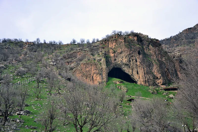 View of a hillside with a large cave opening.