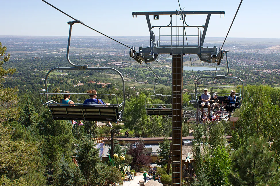 People riding on chairlifts over a mountain slope.
