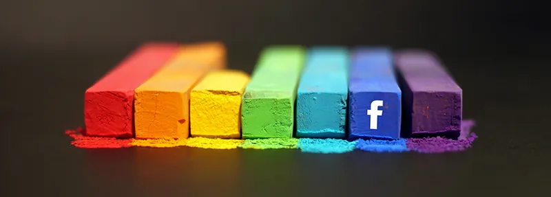 Rectangular pieces of chalk of different lengths are lined up in a row in rainbow order: red, orange, yellow, green, blue, indigo, and violet. The Facebook logo is on the indigo piece of chalk. Chalk dust of each color is in front of each piece of chalk.
