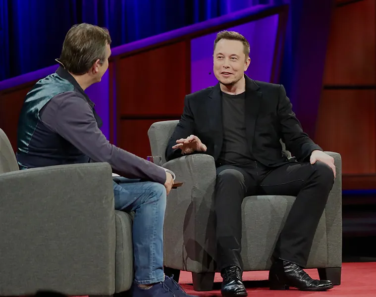 A photo shows Elon Musk in conversation with the host at a Ted X conference.