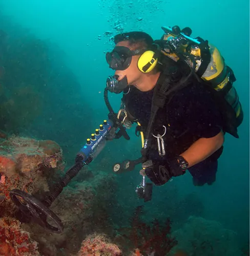 Fotografía de un buceador subacuático utilizando un detector de metales.