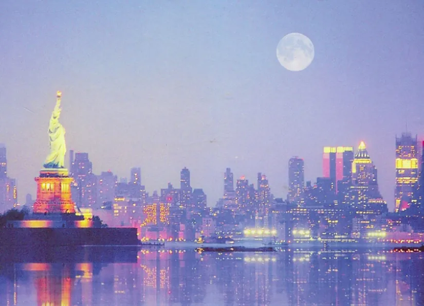 A panorama of New York Harbor at dusk with a full moon in the sky