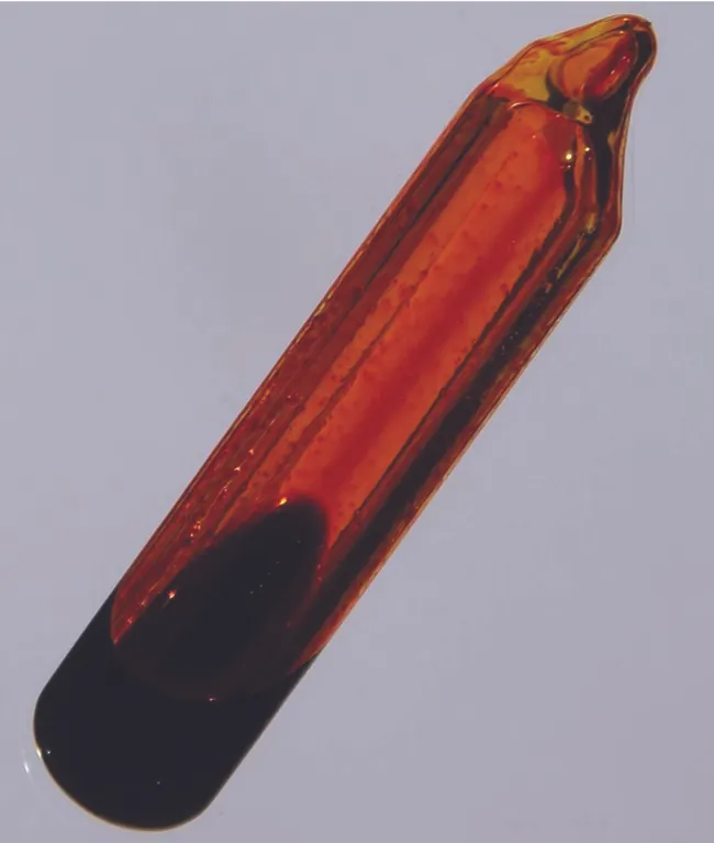 Se muestra un recipiente de vidrio que está lleno de un gas de color marrón anaranjado y una pequeña cantidad de líquido de color naranja oscuro.