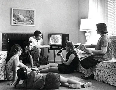 A photograph shows a man, a woman, three teenage girls, and a teenage boy sitting in a living room, watching a television.