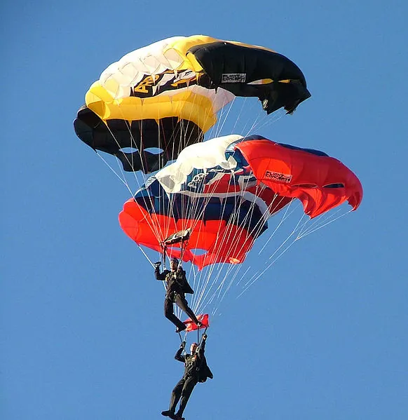 The figure shows two skydivers midway through the air, with both with open having their parachutes open.