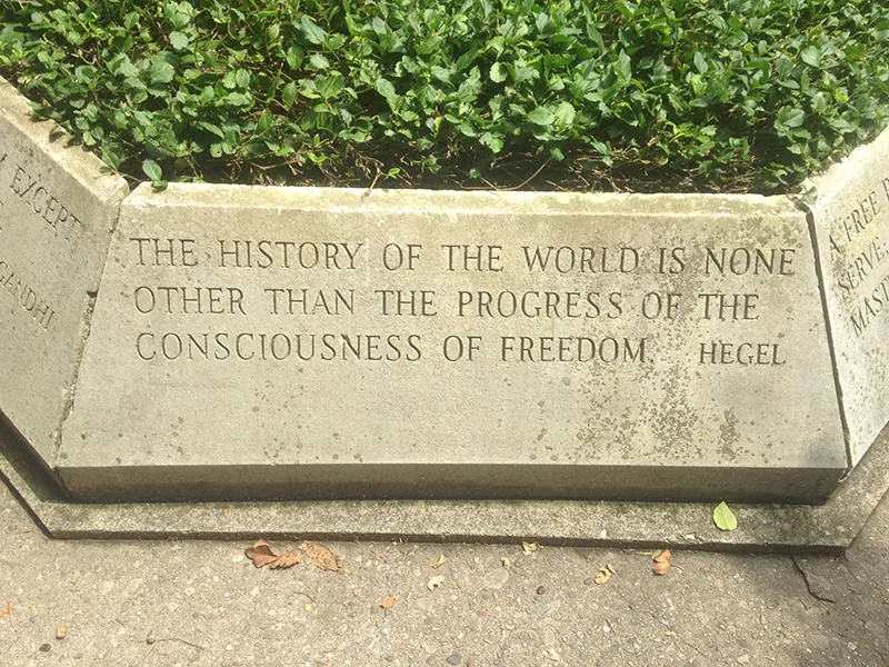 A stone planter carved with the text, “The history of the world is none other than the progress of the consciousness of freedom. - Hegel”